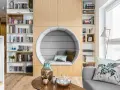 Przytulna domowa biblioteczka z okrągłym fotelem do czytania, pełna książek i gier planszowych.