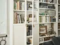 Urocza domowa biblioteczka w małym mieszkaniu, pełna książek, ozdób i pudełek.