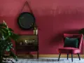 Eleganckie wnętrze w kolorze marsala, z aksamitnym fotelem, lustrem i roślinami.