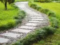 Kamienna, tania ścieżka w ogrodzie, otoczona bujną zielenią.