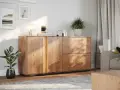 Drewniana komoda w salonie, ozdobiona lampą, świecą i roślinami. Idealne co na komodę w salonie, by stworzyć przytulną atmosferę.