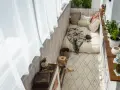 Przytulny balkon w stylu boho: łóżko z kocem, poduszki, dywan, rośliny i drewniane dekoracje. Idealne inspiracje na relaks.