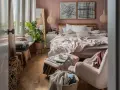 Przytulna sypialnia w stylu boho z dużą ilością roślin, plecionymi lampami i miękkimi tekstyliami.