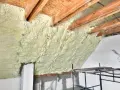 Pianka pur na poddaszu, tworząca grubą warstwę izolacji między drewnianymi belkami. Wygląda na skuteczniejszą niż tradycyjna wełna.