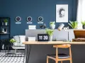 Biuro z zegarami pokazującymi czas w Nowym Jorku, Londynie i Tokio na ścianie w kolorze navy. Na biurku laptop, lampka i gramofon.