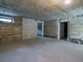 Surowa piwnica ziemna z betonowymi ścianami, białymi ceglanymi wstawkami i oknem. Widać przygotowania do wentylacji piwnicy ziemnej.
