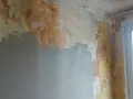 Ściana w trakcie remontu, z fragmentami starej farby i nową warstwą gładzi. Pokazuje, jak położyć gładź na ścianę, przygotowując ją do malowania.