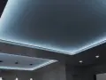 Nowoczesny sufit napinany w salonie z subtelnym, niebieskim podświetleniem LED tworzy relaksującą atmosferę.