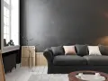 Nowoczesny salon z wygodną kanapą i **czarnymi ścianami**, które nadają mu elegancji. W tle widać okno i dzieła sztuki.