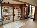 Nowoczesna biblioteczka w stylu bauhaus z ceglaną ścianą, czarnymi krzesłami i dywanem.