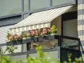 Jak zrobić daszek na balkon? Płócienny markiza chroni przed słońcem, a skrzynki z kwiatami dodają uroku.