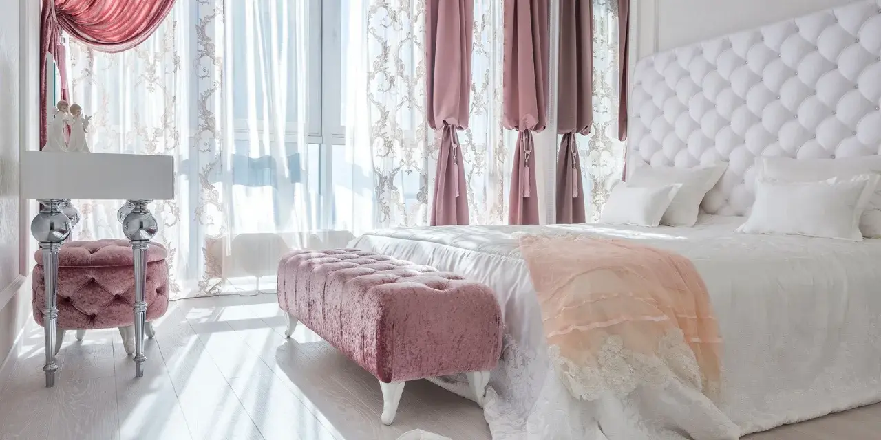 Elegancka sypialnia w stylu angielskim z pikowanym zagłówkiem, różowymi pufami i zasłonami.
