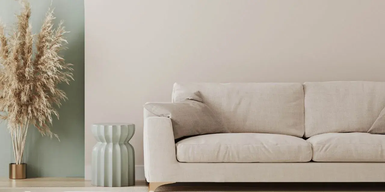 Jasna sofa i dekoracje z traw pampasowych to świetny pomysł na pustą ścianę w salonie.