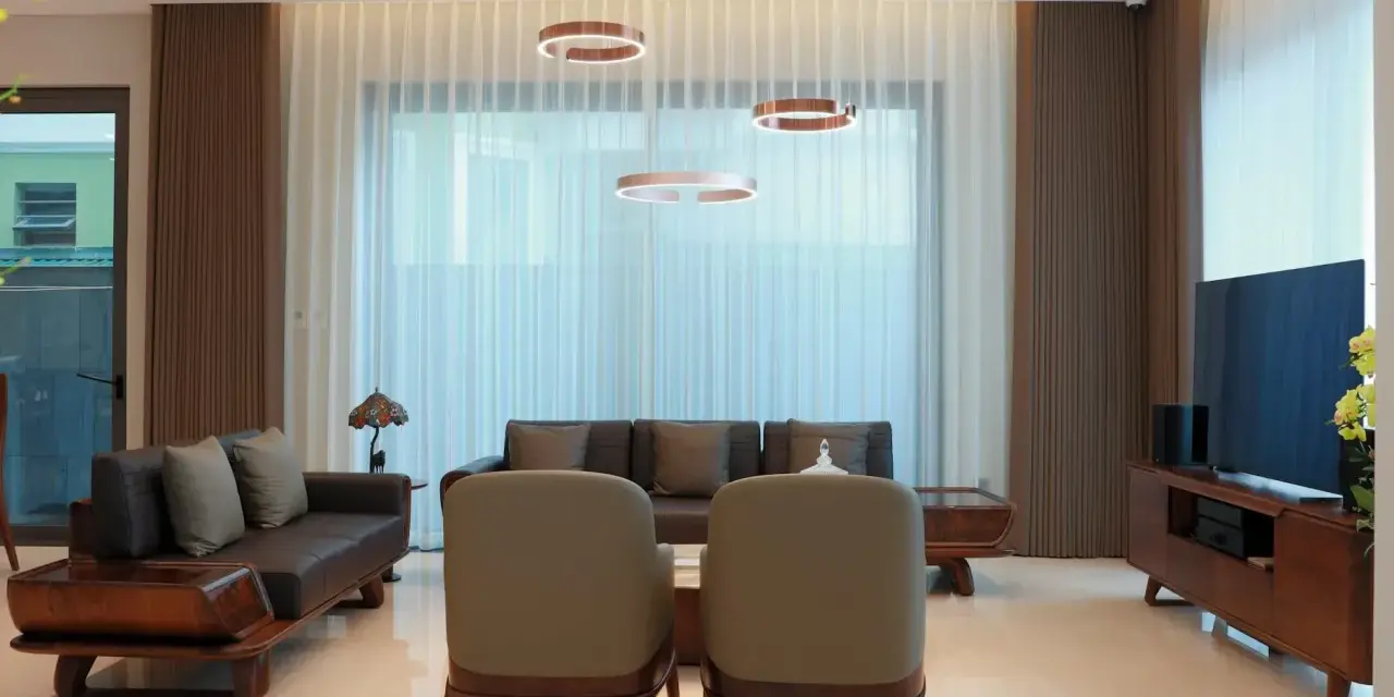 Nowoczesne lampy wiszące nad kanapą i fotelem to klucz do tego, jak rozmieścić oświetlenie w salonie.