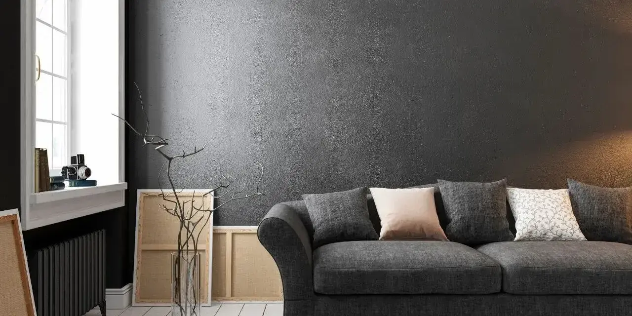 Nowoczesny salon z wygodną kanapą i **czarnymi ścianami**, które nadają mu elegancji. W tle widać okno i dzieła sztuki.