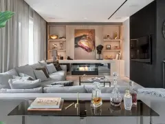 Elegancki salon w stylu nowojorskim z wygodną szarą sofą, nowoczesnym kominkiem i dziełem sztuki.