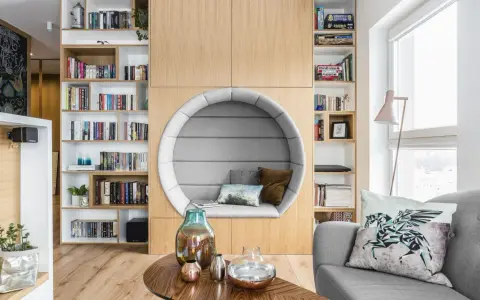 Przytulna domowa biblioteczka z okrągłym fotelem do czytania, pełna książek i gier planszowych.