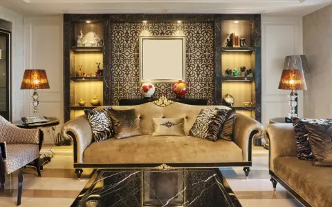 Elegancki salon w stylu art deco z beżową kanapą, ozdobnymi poduszkami i marmurowym stolikiem.