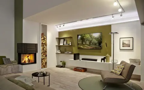 Nowoczesny salon z palącym się kominkiem i telewizorem na jednej ścianie. Obok kominka stos drewna, a na ścianie półki z dekoracjami.