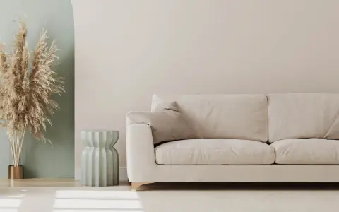 Jasna sofa i dekoracje z traw pampasowych to świetny pomysł na pustą ścianę w salonie.