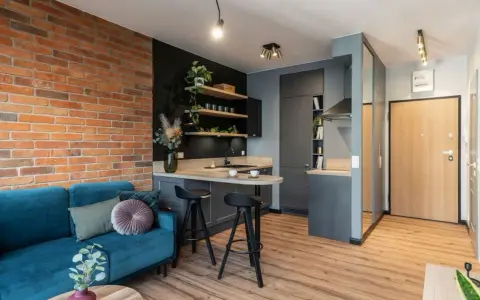 Nowoczesne mieszkanie 35m2 plan: kanapa, kuchnia z wyspą, ceglana ściana i drzwi.
