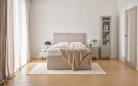 Beżowa sypialnia inspiracje: przytulne łóżko z narzutą, jasne zasłony i minimalistyczne meble tworzą spokojną atmosferę.
