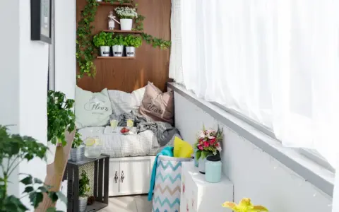 Przytulny balkon typu loggia z wygodną kanapą, ziołami na drewnianej ścianie i bukietem kwiatów. Idealne miejsce na relaks.