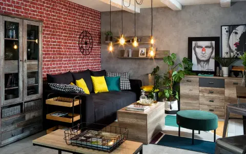 Męski pokój inspiracje: loftowy klimat z ceglaną ścianą, czarną kanapą, drewnianymi meblami i industrialnymi lampami.