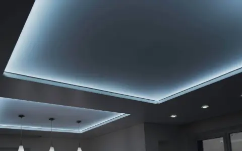 Nowoczesny sufit napinany w salonie z subtelnym, niebieskim podświetleniem LED tworzy relaksującą atmosferę.