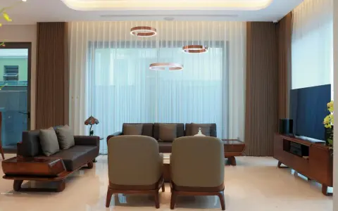 Nowoczesne lampy wiszące nad kanapą i fotelem to klucz do tego, jak rozmieścić oświetlenie w salonie.