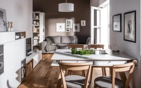 Nowoczesny salon z szarą kanapą i brązowymi drewnianymi elementami. Czy kolor szary pasuje do brązu? Tak, tworzy przytulną atmosferę.
