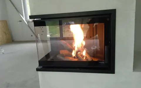 Nowoczesny kominek w rogu z palącym się ogniem i polanami. Ciepło i przytulność w nowym domu.