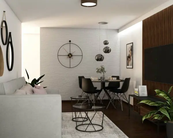 Nowoczesny salon z szarą kanapą, okrągłym stołem i czarnymi krzesłami. W tle biała ceglana ściana z dużym zegarem. Ciemna, brązowa podłoga w salonie dodaje elegancji.