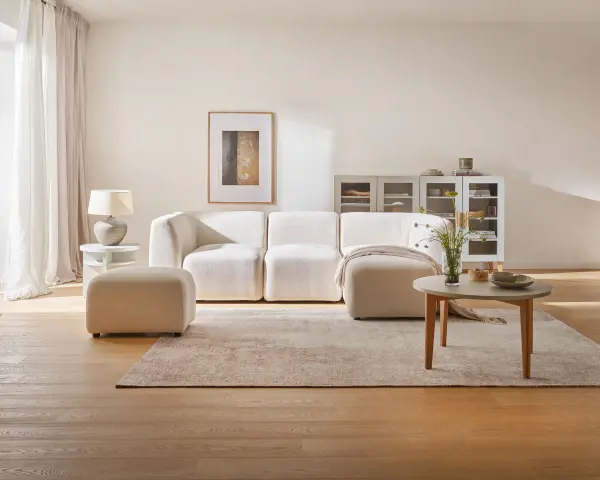 Jasny salon z beżową sofą i pufą. Kolor beżowy z czym łączyć? Z bielą, drewnem i pastelami.
