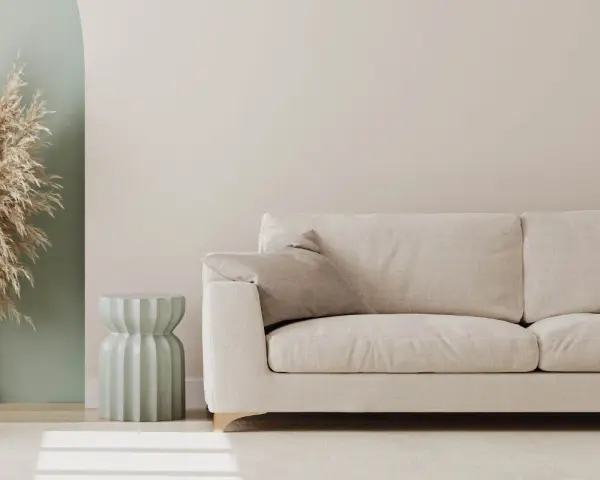 Jasna sofa i dekoracje z traw pampasowych to świetny pomysł na pustą ścianę w salonie.