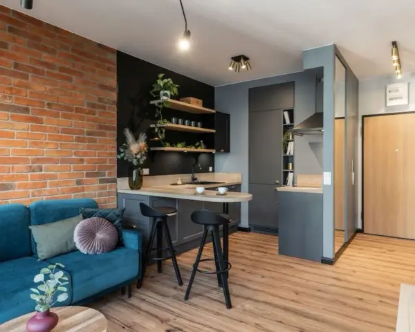 Nowoczesne mieszkanie 35m2 plan: kanapa, kuchnia z wyspą, ceglana ściana i drzwi.