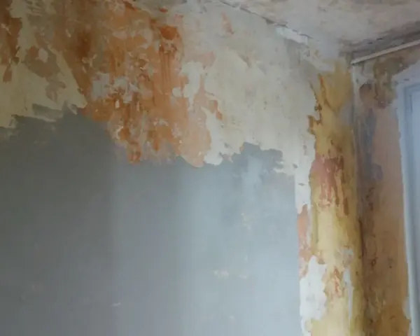 Ściana w trakcie remontu, z fragmentami starej farby i nową warstwą gładzi. Pokazuje, jak położyć gładź na ścianę, przygotowując ją do malowania.