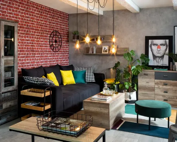 Męski pokój inspiracje: loftowy klimat z ceglaną ścianą, czarną kanapą, drewnianymi meblami i industrialnymi lampami.