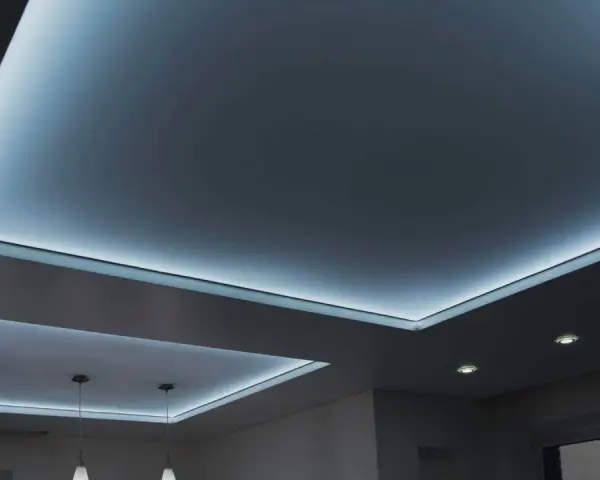 Nowoczesny sufit napinany w salonie z subtelnym, niebieskim podświetleniem LED tworzy relaksującą atmosferę.