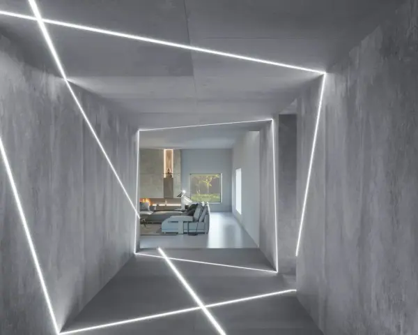 Nowoczesny korytarz z betonowymi ścianami i sufitem, ozdobiony geometrycznym, liniowym podświetleniem. Świetny pomysł na podświetlenie ściany, tworzący futurystyczny efekt.