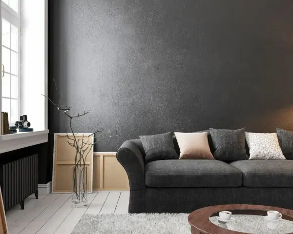 Nowoczesny salon z wygodną kanapą i **czarnymi ścianami**, które nadają mu elegancji. W tle widać okno i dzieła sztuki.