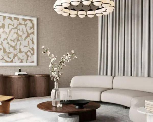 Salon w stylu modern classic z zakrzywioną sofą, drewnianym fotelem i okrągłym stolikiem.