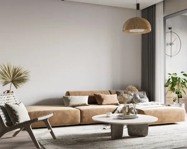 Wabi-sabi wnętrza: beżowa kanapa, pleciony fotel, suszone trawy i palma tworzą przytulną, naturalną przestrzeń.