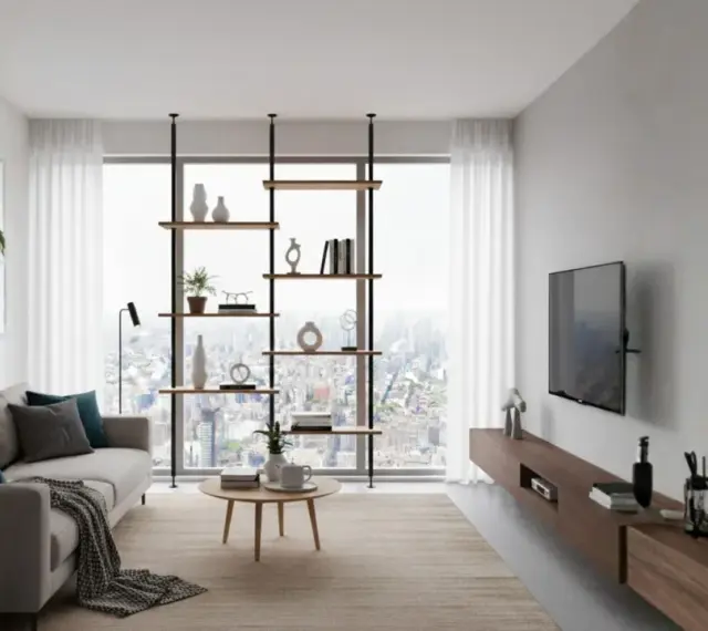 Nowoczesny salon prostokątny jak urządzić: szara sofa, drewniana komoda, regał z dekoracjami i widok na miasto.