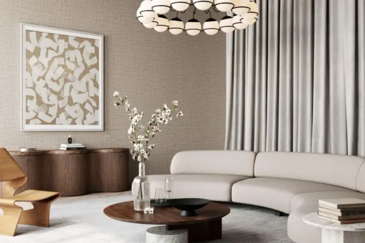 Salon w stylu modern classic z zakrzywioną sofą, drewnianym fotelem i okrągłym stolikiem.