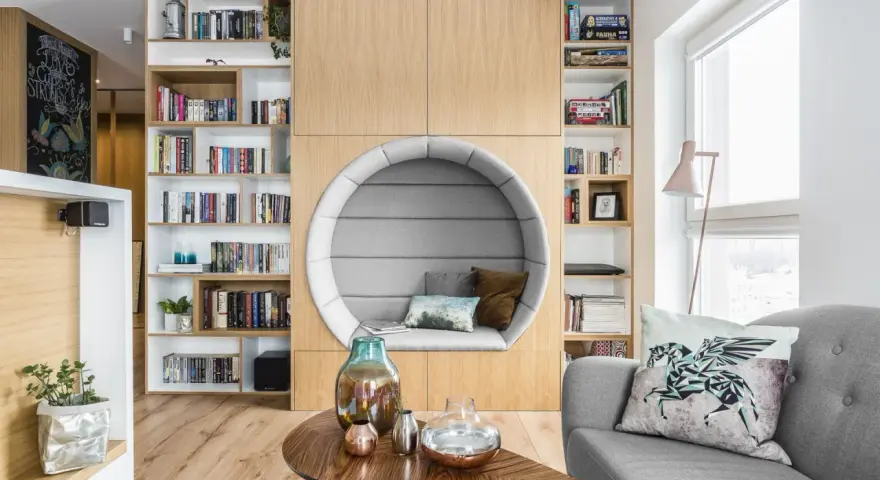 Przytulna domowa biblioteczka z okrągłym fotelem do czytania, pełna książek i gier planszowych.