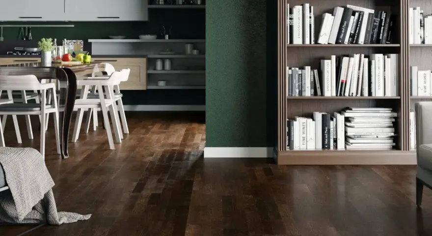 Nowoczesny salon z ciemną podłogą, kuchnią i regałem pełnym książek.