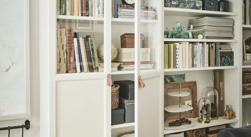 Urocza domowa biblioteczka w małym mieszkaniu, pełna książek, ozdób i pudełek.