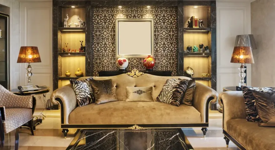 Elegancki salon w stylu art deco z beżową kanapą, ozdobnymi poduszkami i marmurowym stolikiem.