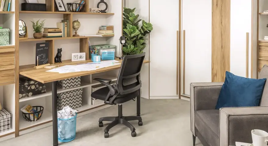 Ukryte biurko w salonie, z czarnym krzesłem i półkami pełnymi książek i dekoracji.